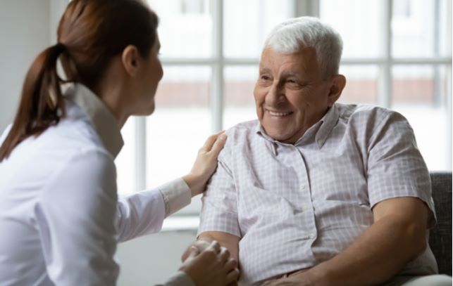 Happy senior man accompanied by nurse in senior community