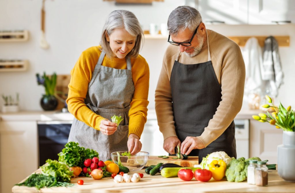 Elderly couple preparing a salad together.