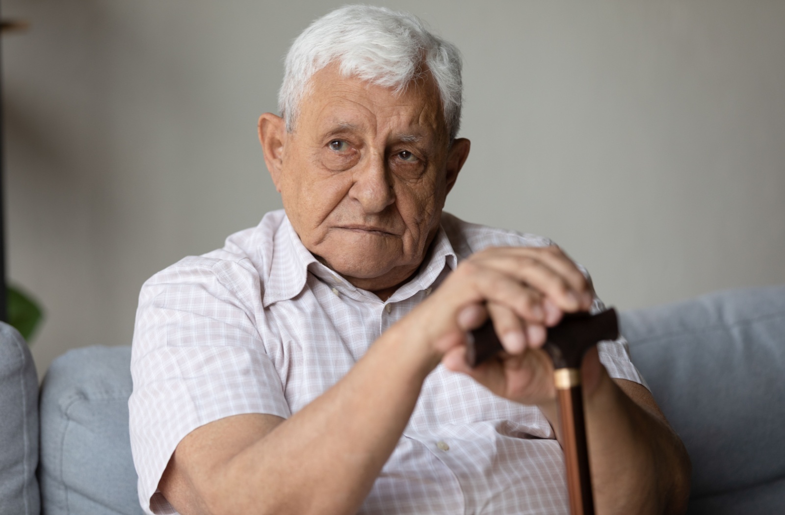 Older man sitting on couch with cane.