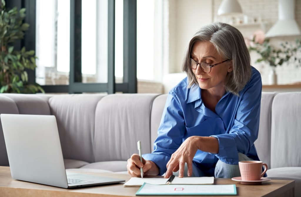 An older adult taking notes at their laptop during a cognitive training exercise.