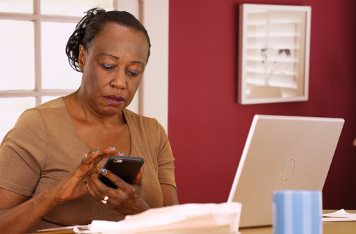A woman working on her laptop and phone to determine her potential tax deductions