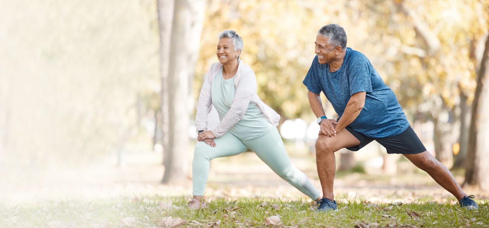 A happy senior couple exercising together outdoors in a park.