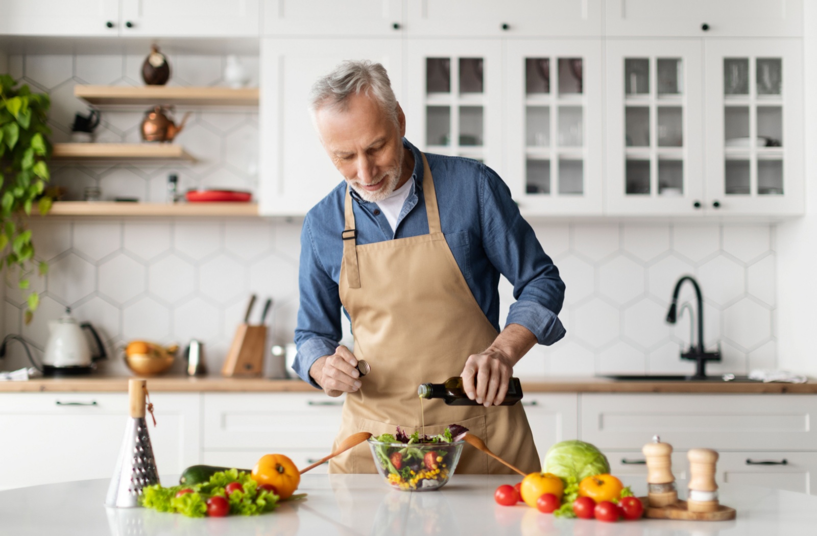 senior man adds oil to his salad