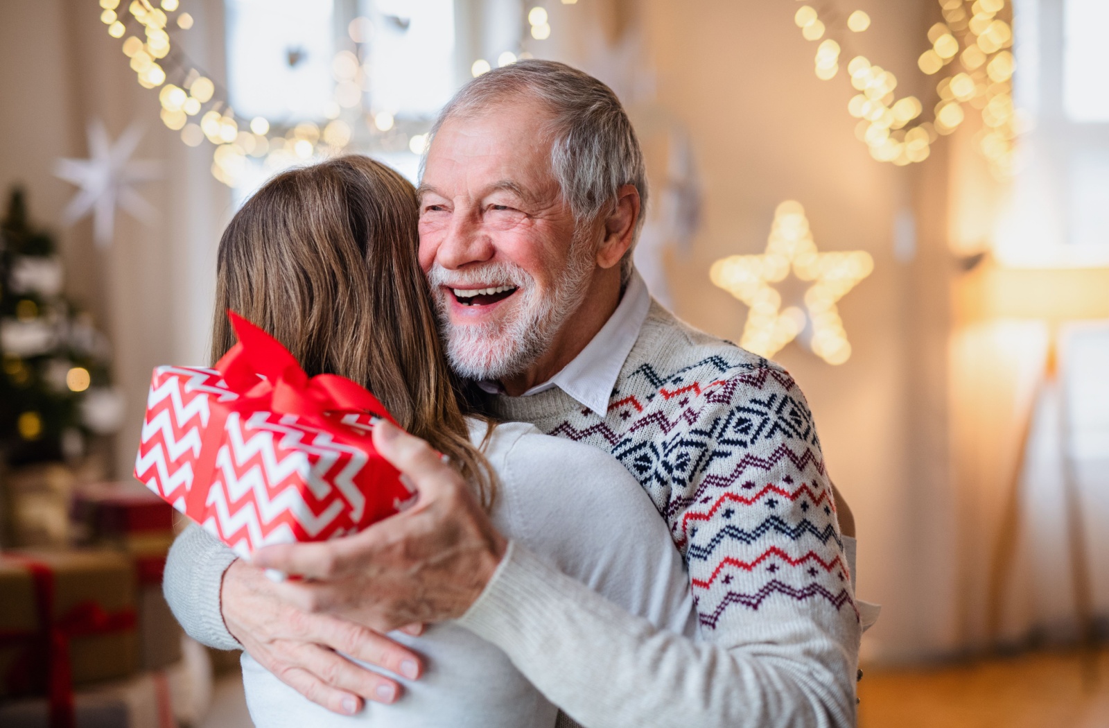 An older adult with cognitive decline receives a holiday present from their adult child.
