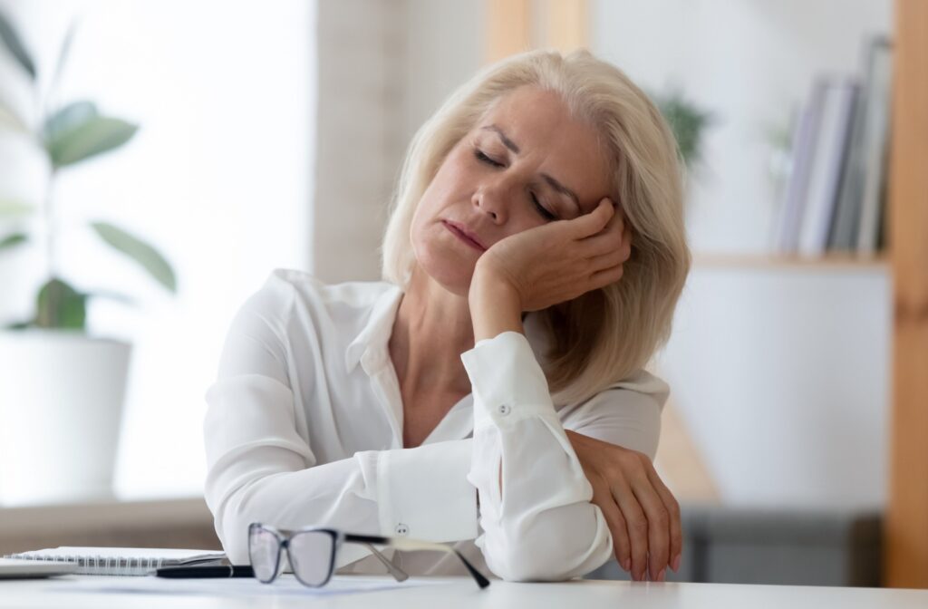 exhausted senior woman sleeping at her desk.