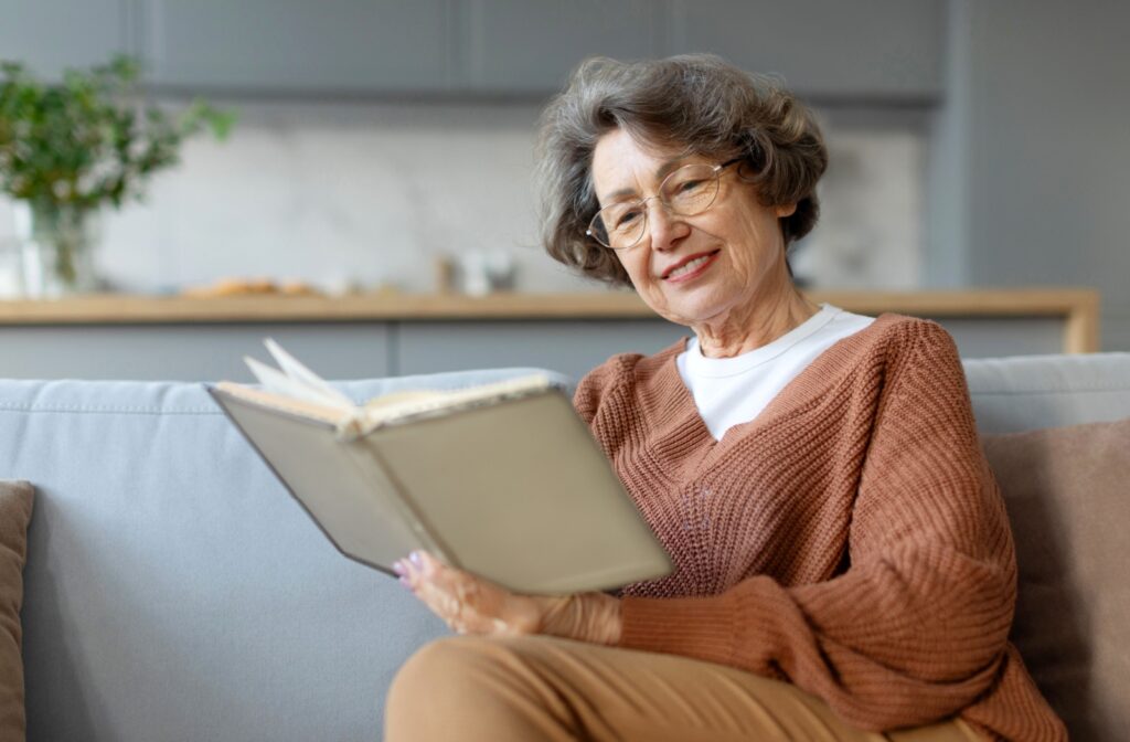 Smiling senior woman reading a book on the couch.