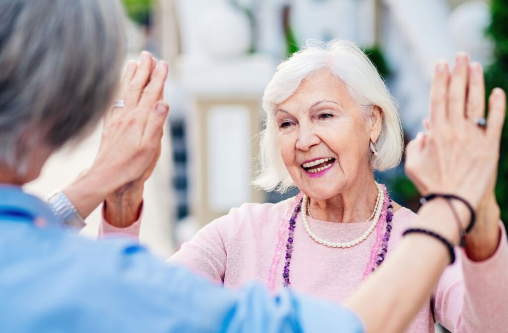 A senior with dementia double high-fives a fellow resident in memory care, getting fulfillment out of a sense of community.