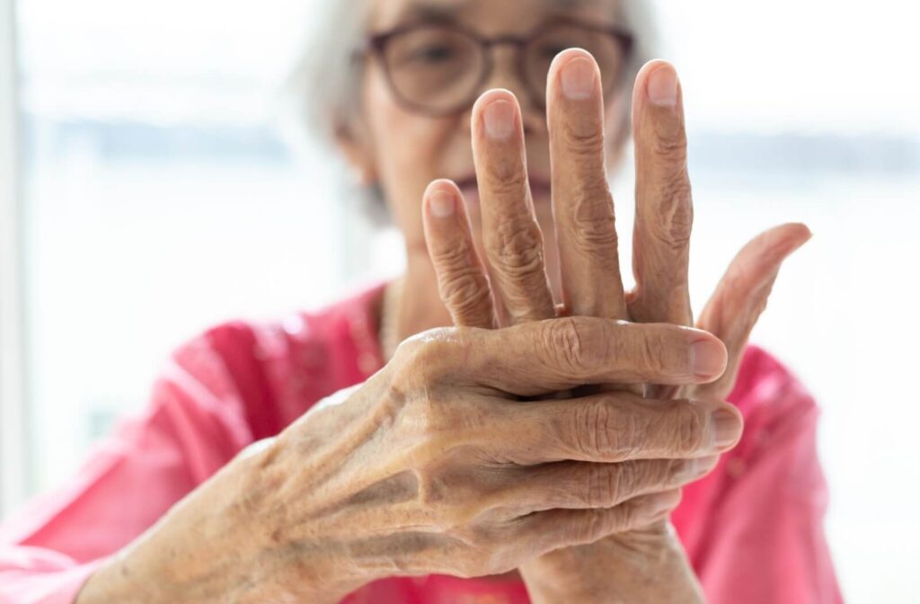 A senior holds up one hand to massage it with the other, priming it for little stretches to improve mobility