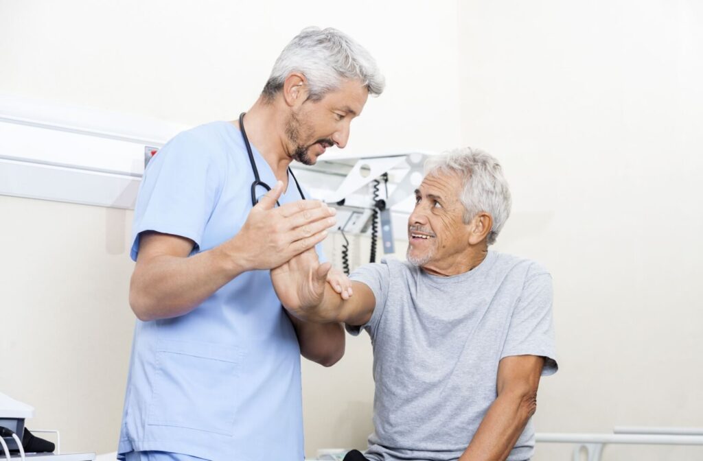 A senior sees a physiotherapist to help learn how to best perform hand exercises that they can do on their own