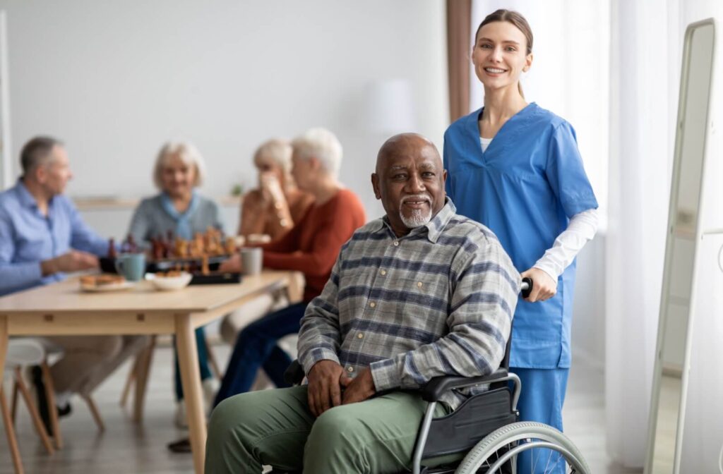 A nurse helps a senior use a wheelchair to get around the communal areas of their assisted living home